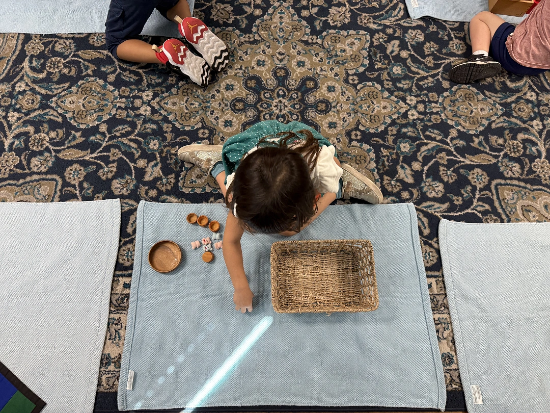 Child playing with small objects on a classroom mat
